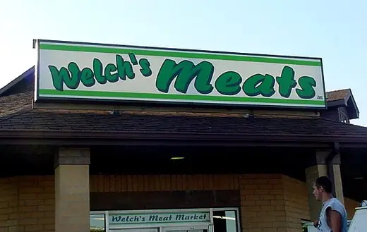 Green storefront fascia sign above a shop entrance